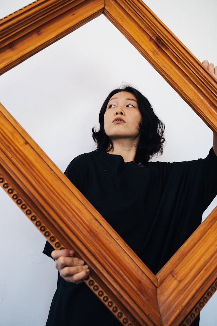 Woman In Black Oversized Shirt Holding A Brown Wooden Frame