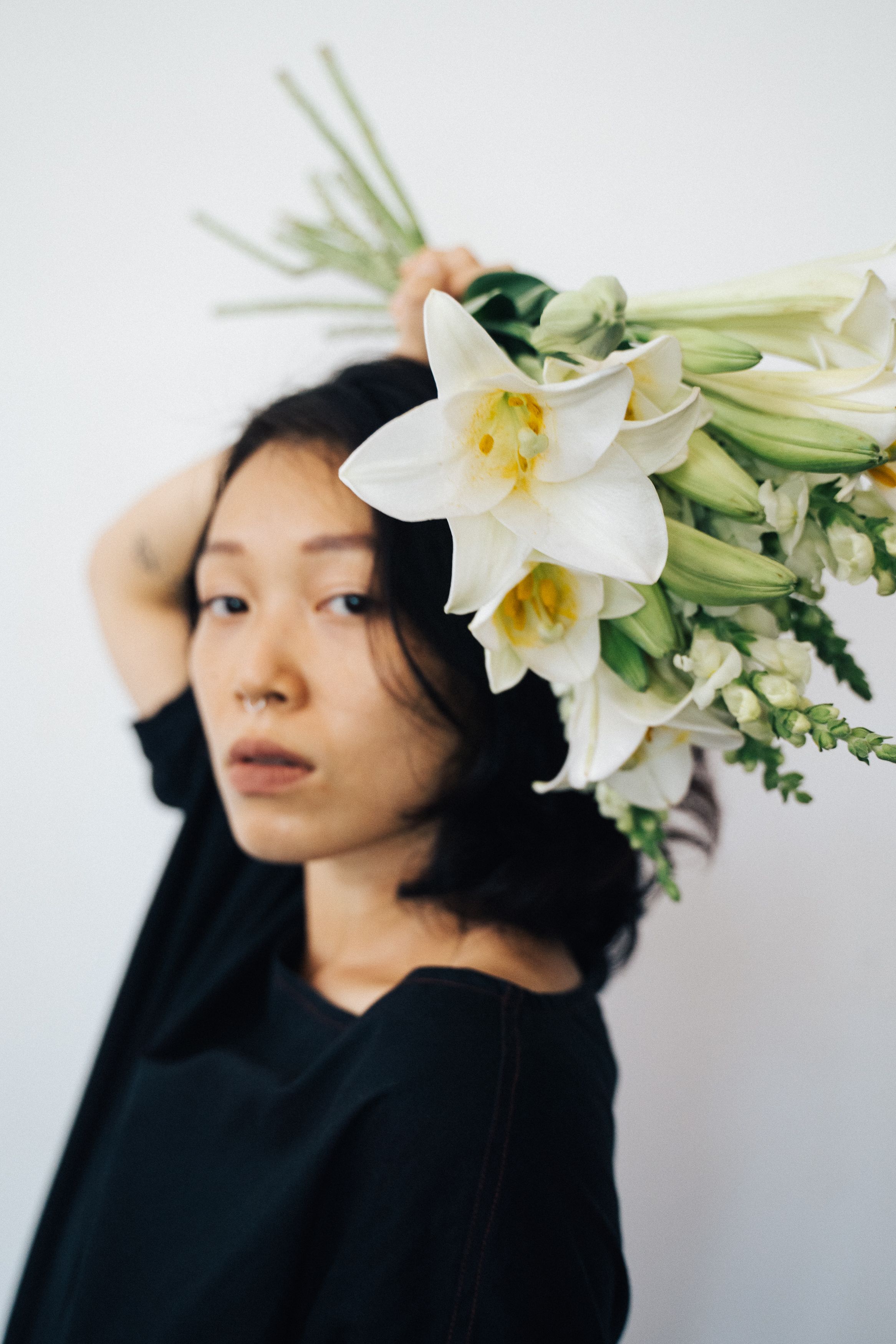 Stylish portrait of an Asian woman with a bouquet of white lilies adding artistic flair.