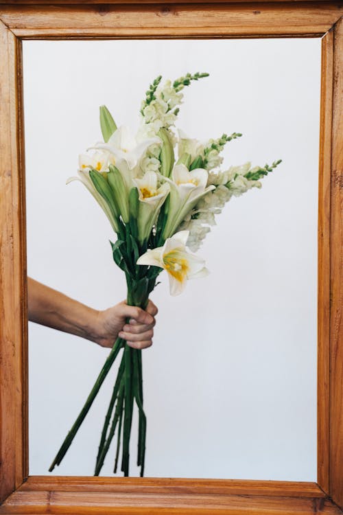 Person Holding White and Yellow Flowers