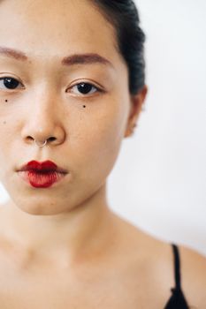 Striking close-up portrait of a woman wearing bold red lipstick and a nose ring.