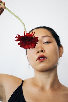 Close-up portrait of a woman with a red flower, striking visual style.