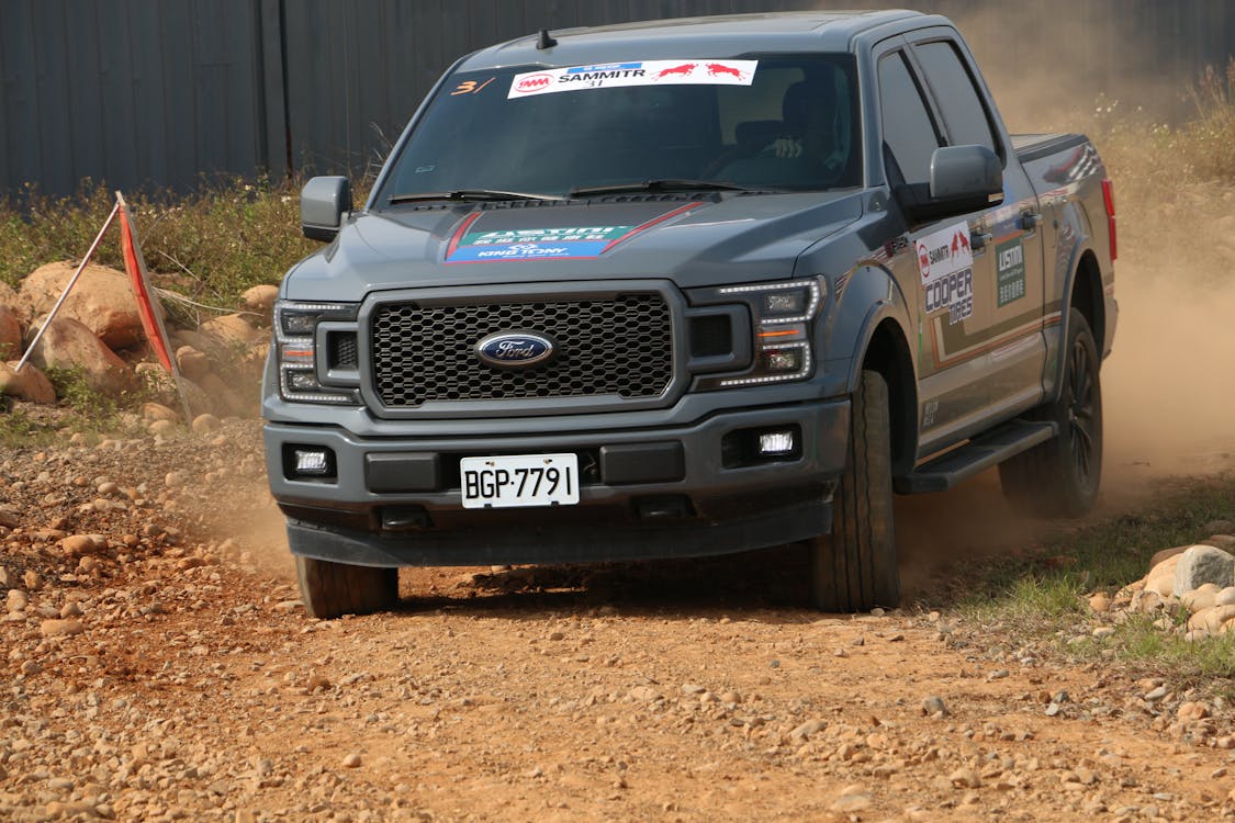 Person Driving a Black Ford F 150 on Dirt Road