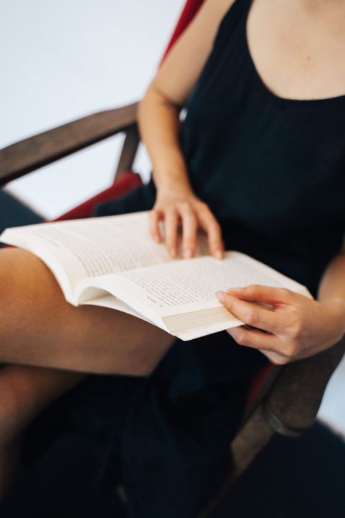 Free A woman sitting and reading a book, focusing on her hands and the open book. Stock Photo