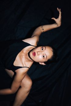 Fashion model striking a dynamic pose with dramatic lighting against a dark background.