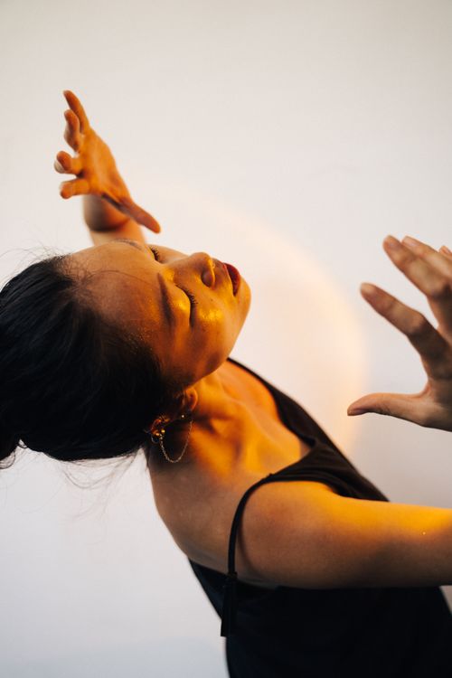 Free A woman gracefully posing in a warm light, expressing artistic elegance and style. Stock Photo