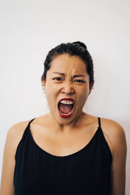 Close-up portrait of a woman expressing intense emotion by yelling. Highlighting facial features and expressions.