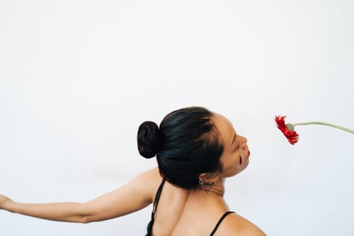 Free Elegant side profile of a woman with a bun and a vibrant red flower. Stock Photo