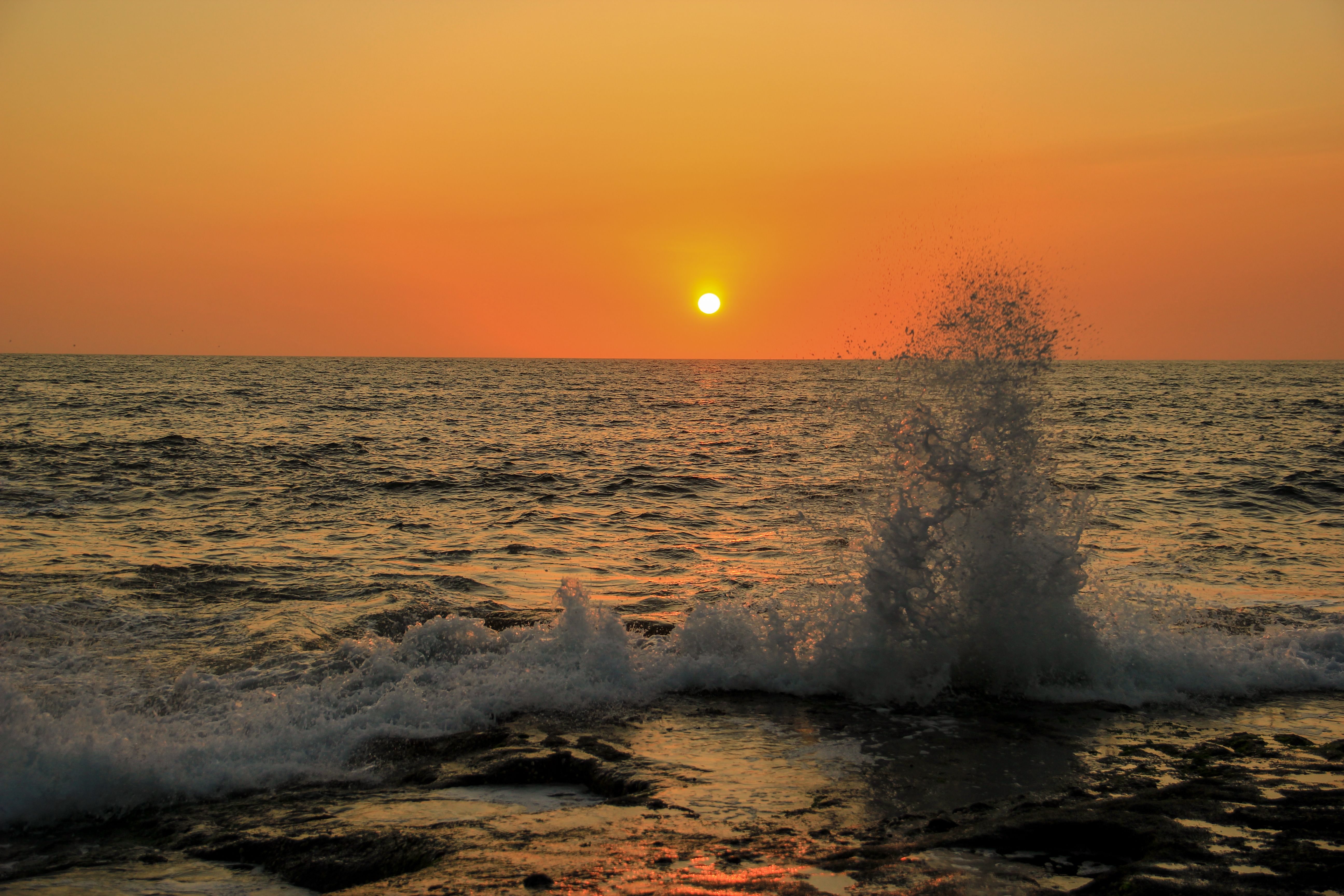Fotomural Capturando el impresionante atardecer sobre las olas que rompen en una playa de Bali con un cielo naranja.