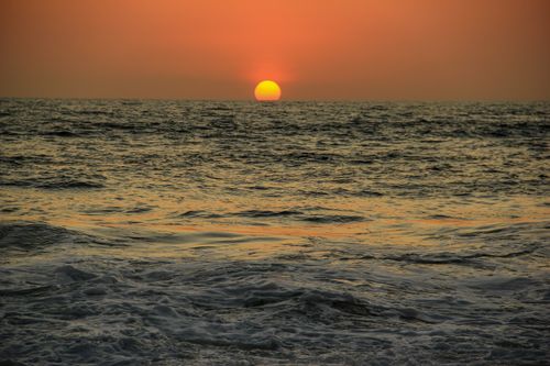 Free Tranquil ocean sunset in Bali with vibrant orange horizon and calm waves. Stock Photo