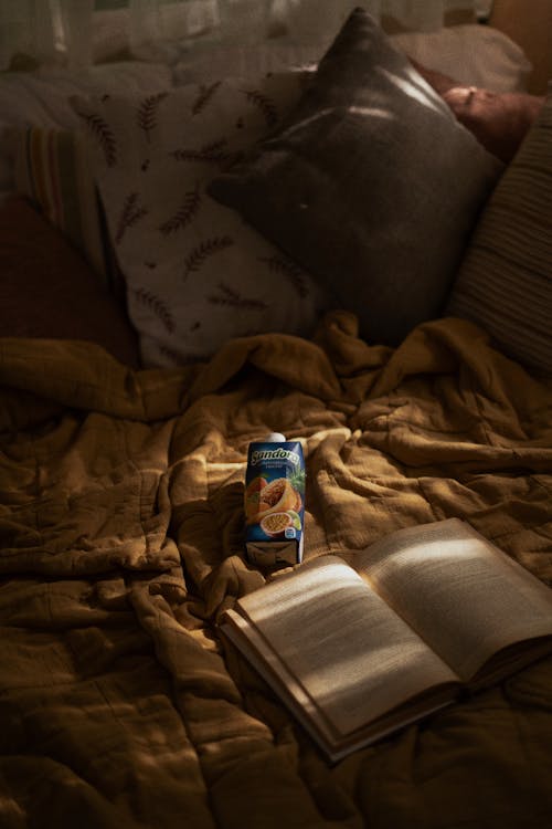 Open Book and a Drink in a Box on a Bed 