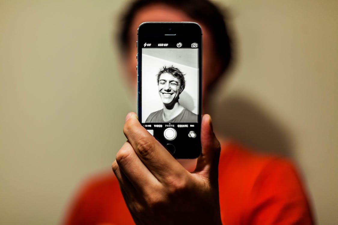 Free Man in Red Shirt Having Selfie on His Iphone in Grayscale Mode Stock Photo