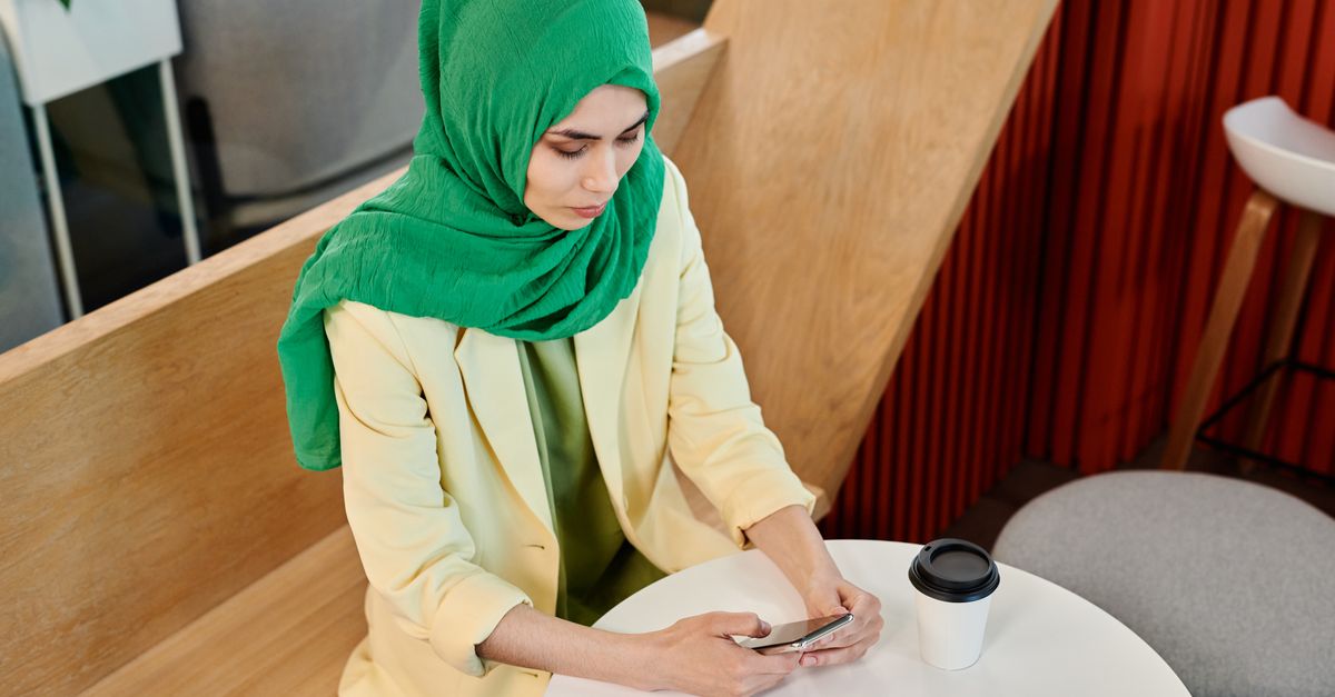 person sitting in coffee shop staring at phone with multiple notifications, candid documentary style