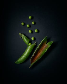 A close-up of fresh green peas arranged on a dark backdrop, highlighting their natural simplicity.