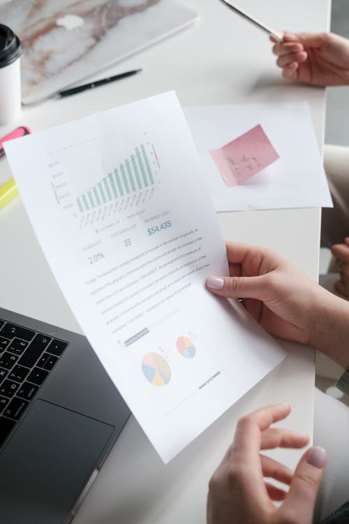 Free Close-up of Woman Holding Documents with Graphs Stock Photo