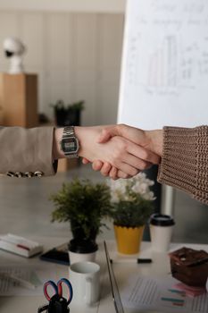 Close-up of a professional handshake between two adults in a contemporary office environment.