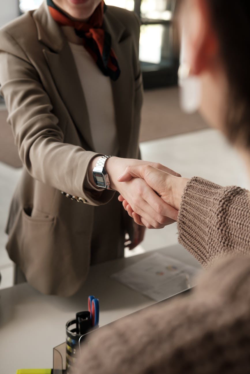 Two professionals shaking hands in an office, signifying a successful business agreement.
