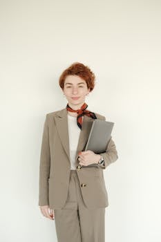 Professional businesswoman in elegant suit holding a laptop with a confident smile, perfect for corporate and office settings.