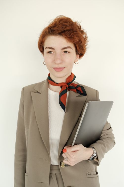 Free Portrait of a stylish businesswoman in suit holding a laptop, exuding confidence and success. Stock Photo
