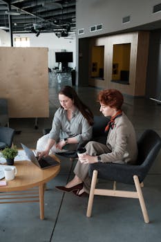 Two women engaged in a business discussion with a laptop in a contemporary office.