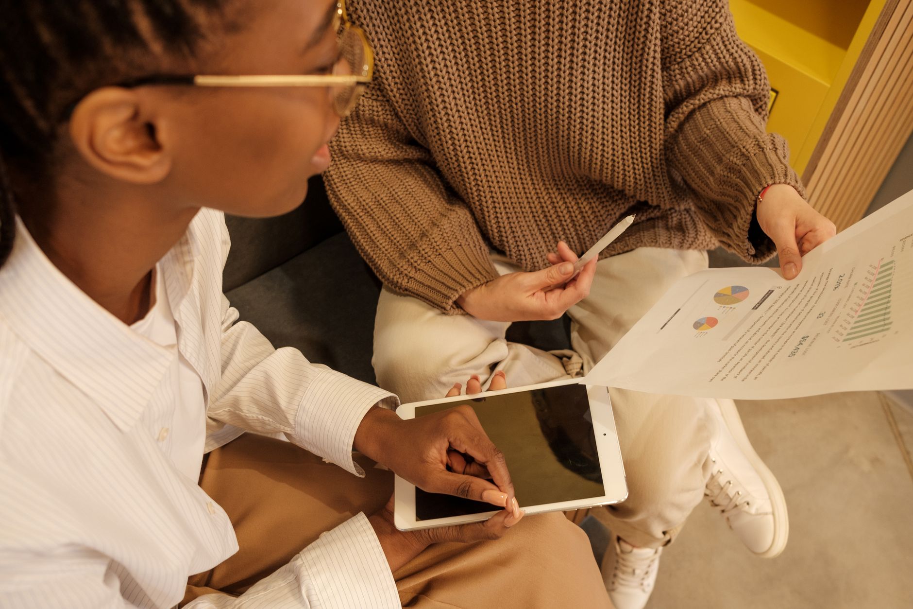 Two professionals discussing documents and data on a tablet during a business meeting.