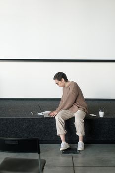 Woman with short hair typing on a laptop while seated indoors.
