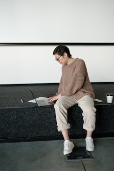A relaxed businesswoman working on a laptop while sitting casually in a modern office.