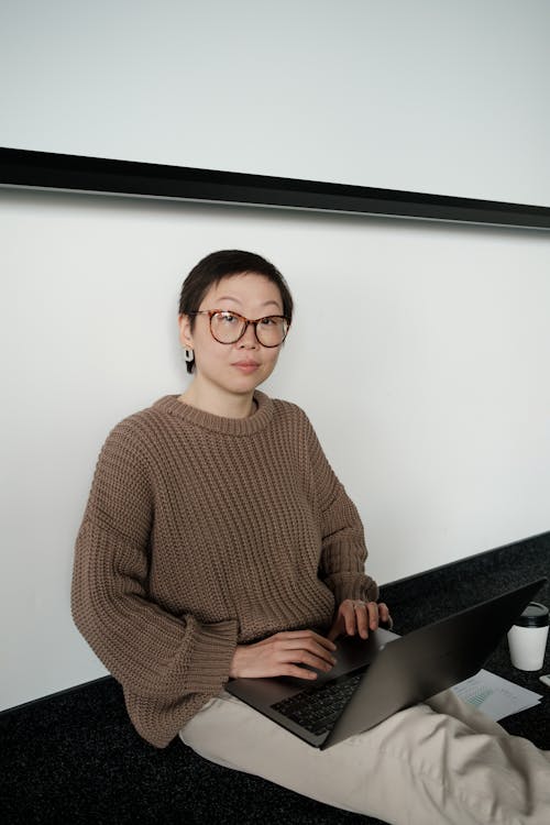 Kostnadsfri bild av asiatisk kvinna, bärbar dator, brun tröja
