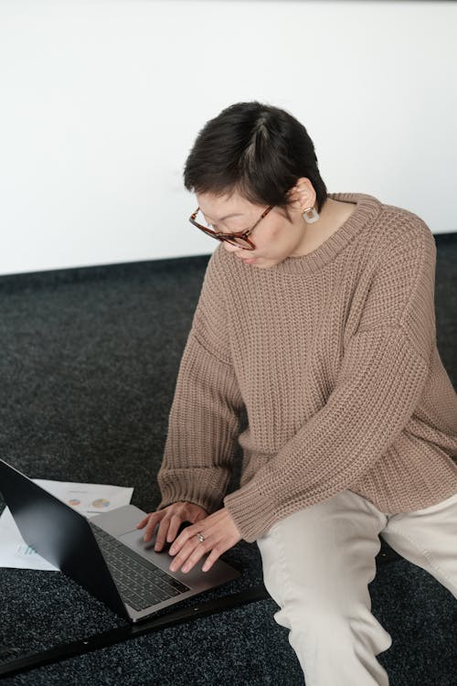 Woman in Brown Sweater Using a Laptop