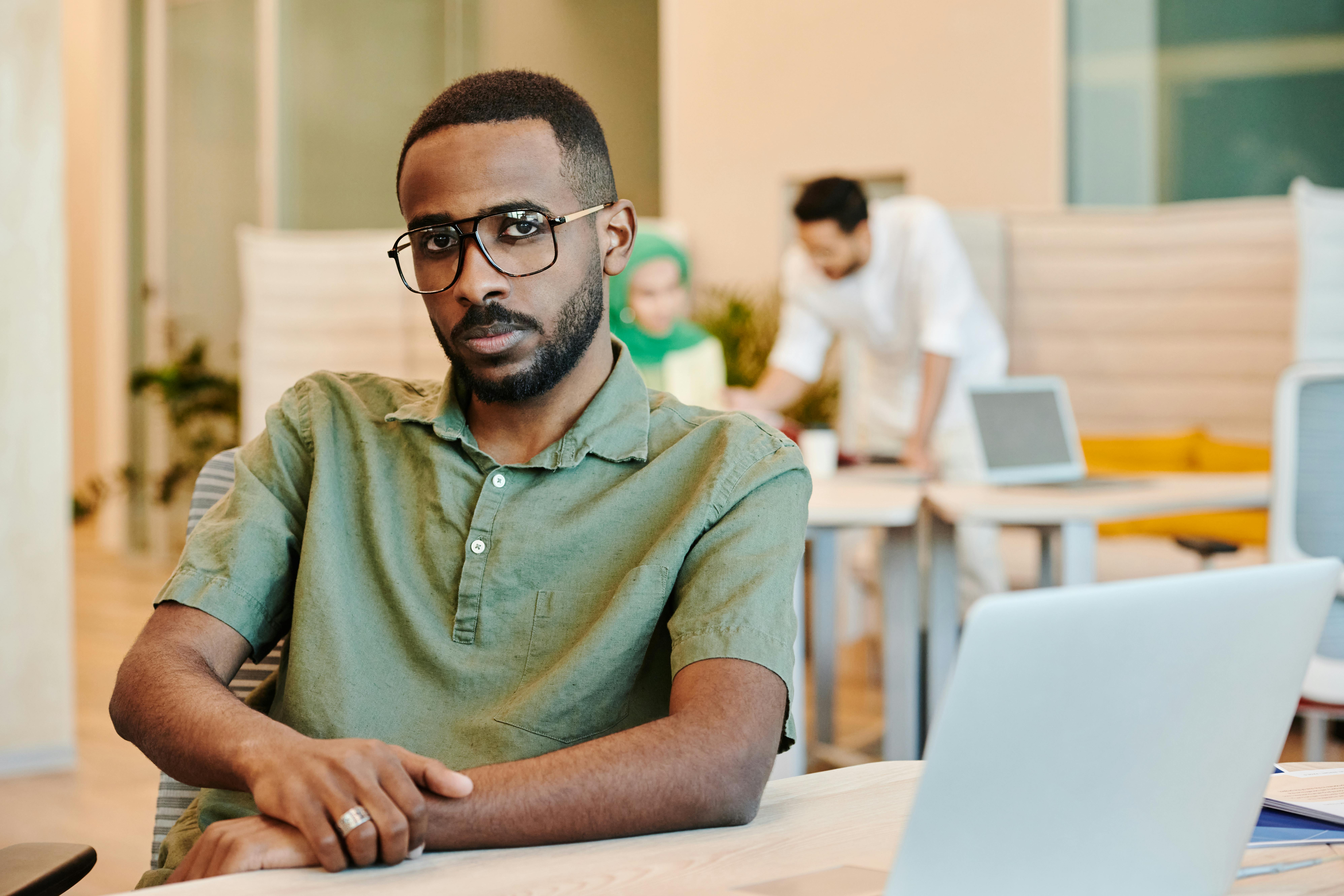 A focused male professional working in a modern office environment with colleagues.
