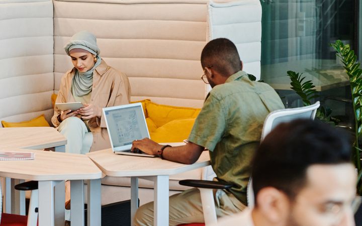 A diverse group of professionals working with technology in a modern office space, fostering collaboration and productivity.