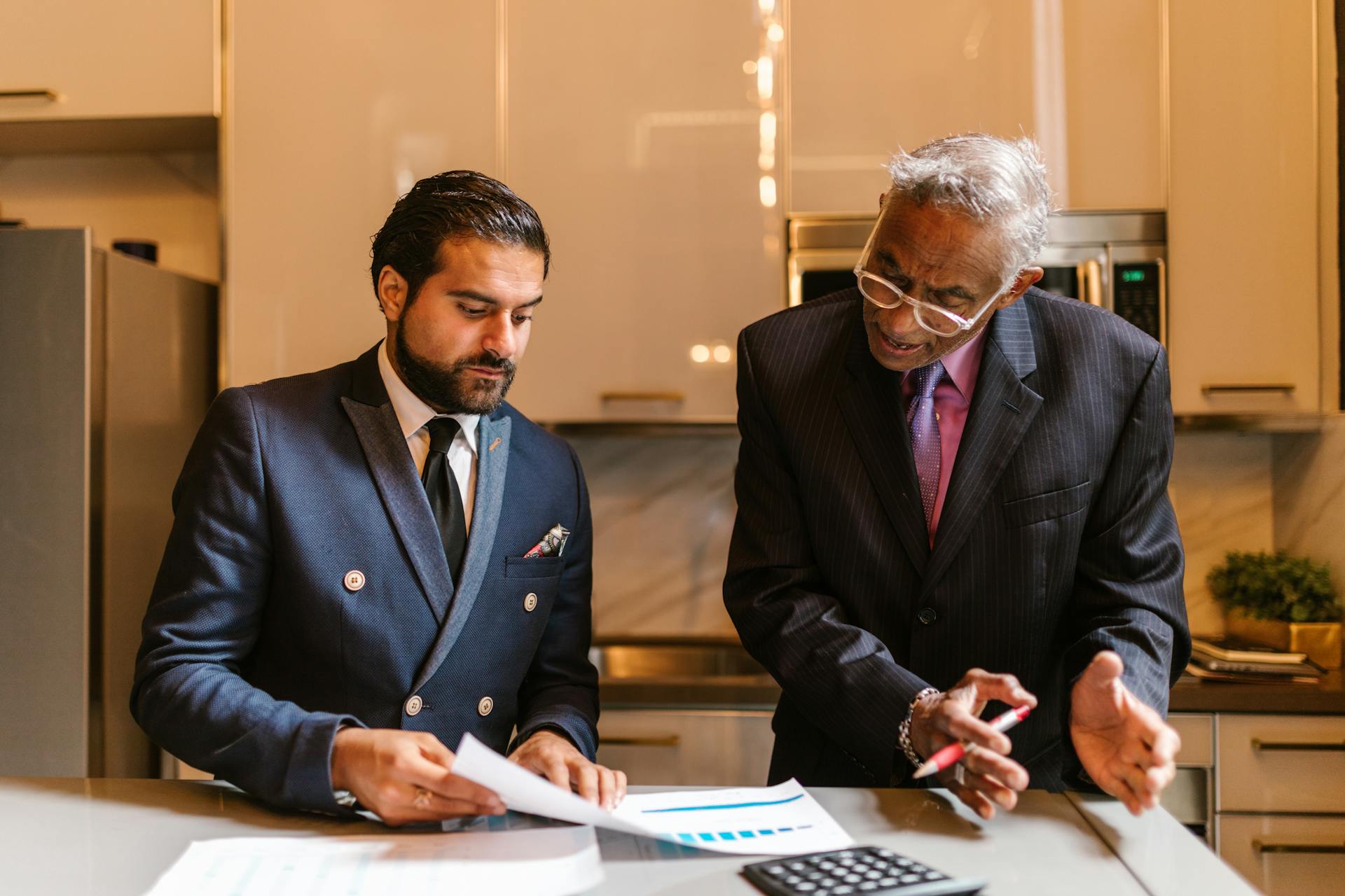 Two businessmen engaged in a focused discussion over financial documents in a modern office setting.