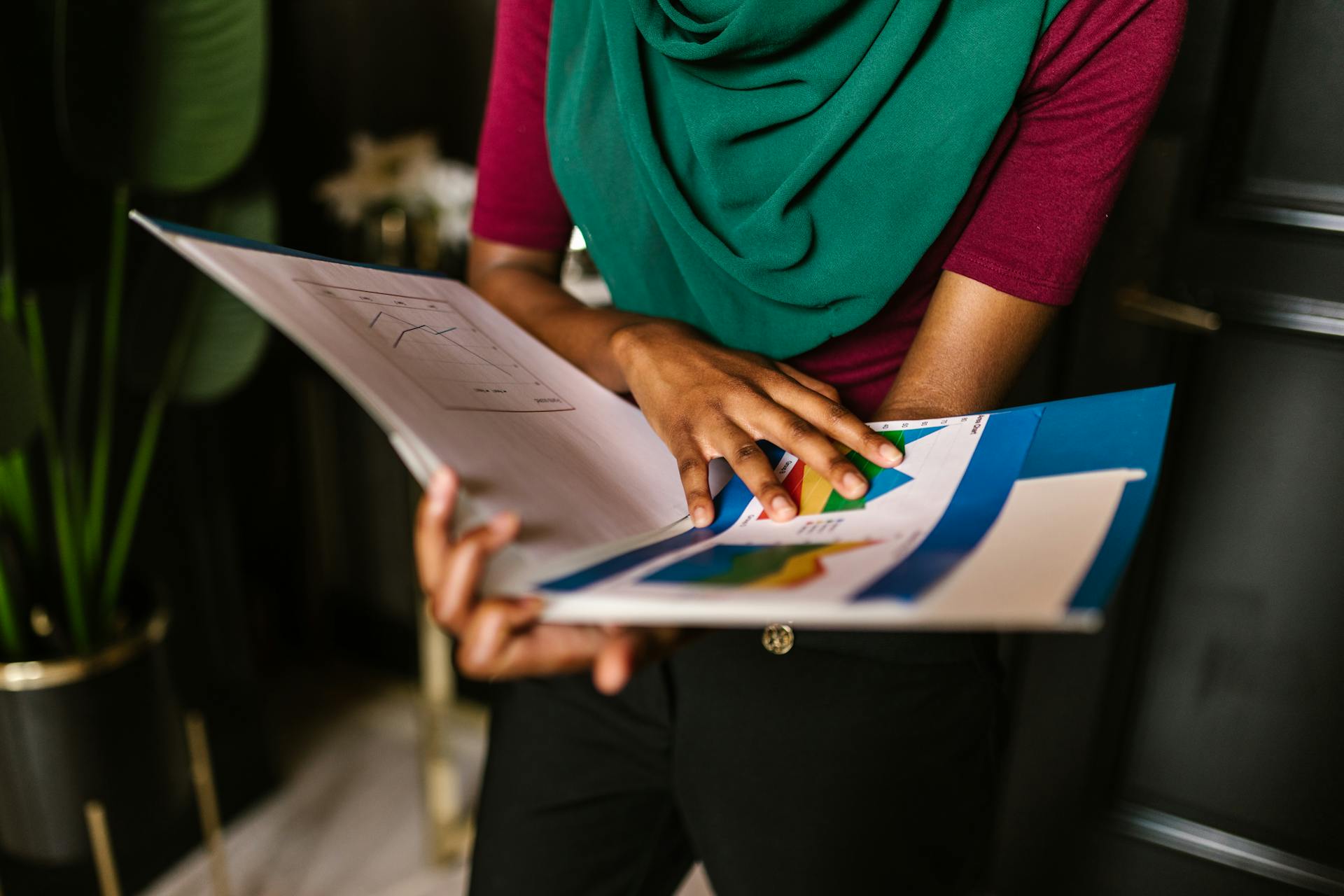 Close-up of a person reviewing charts and reports in an office setting.