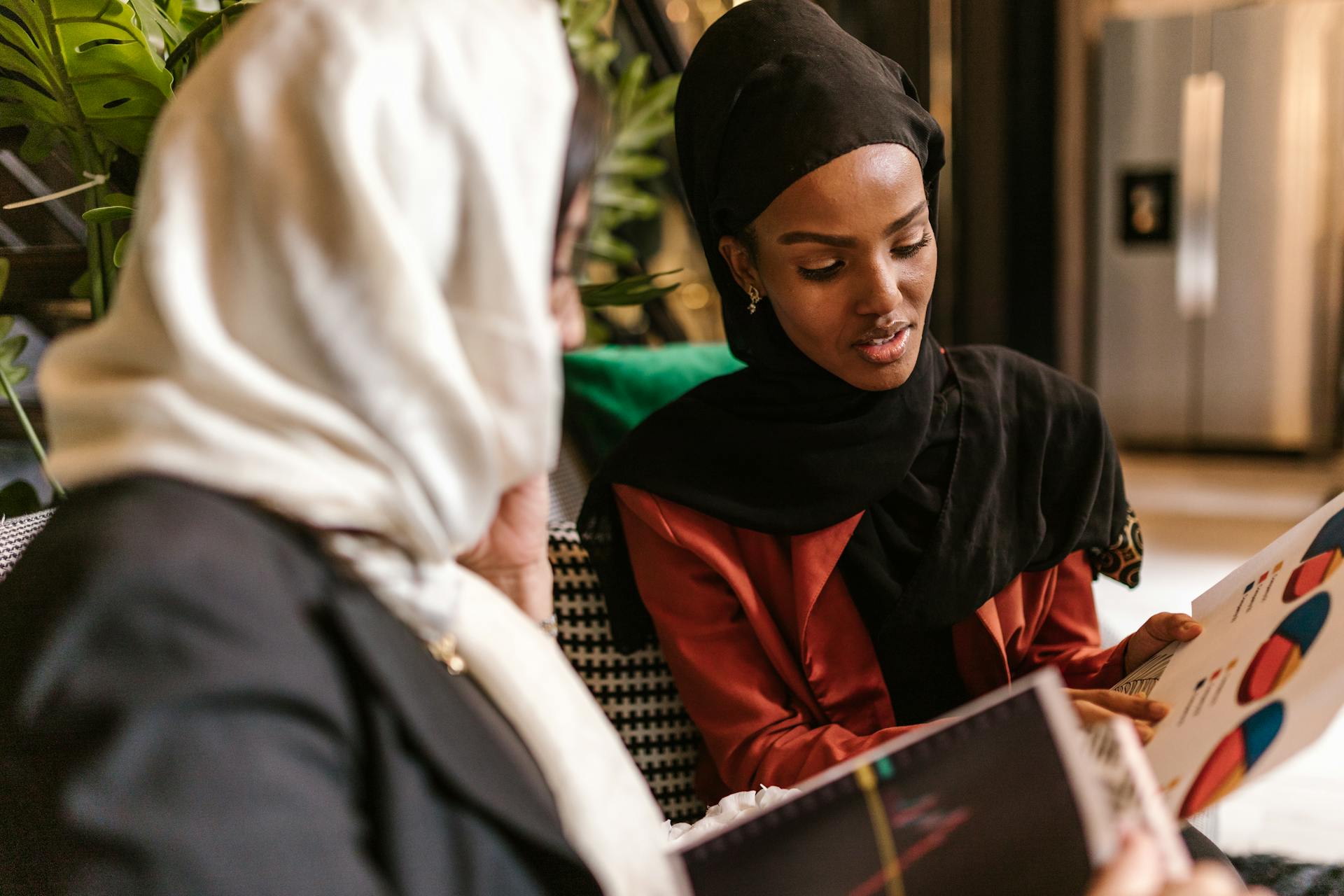 Two Businesswomen in Headscarves Discussing Charts