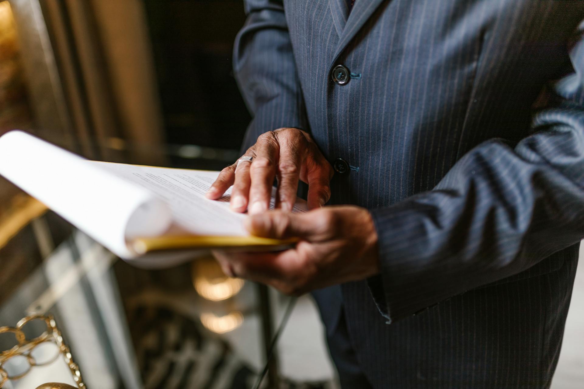 Close-up of a businessman in a suit attentively reviewing a document indoors.