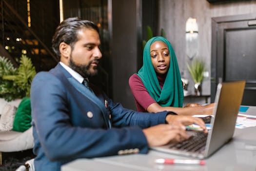 Asian man and black woman in business attire collaborating in modern office.