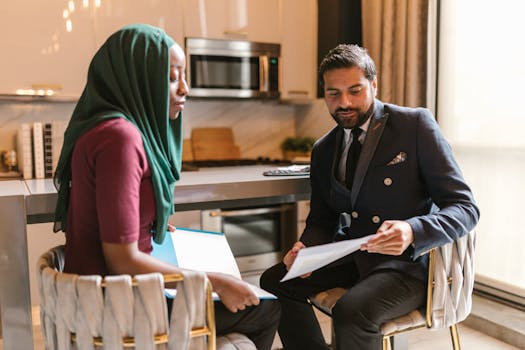 Professionals discussing documents in a contemporary office kitchen setting.