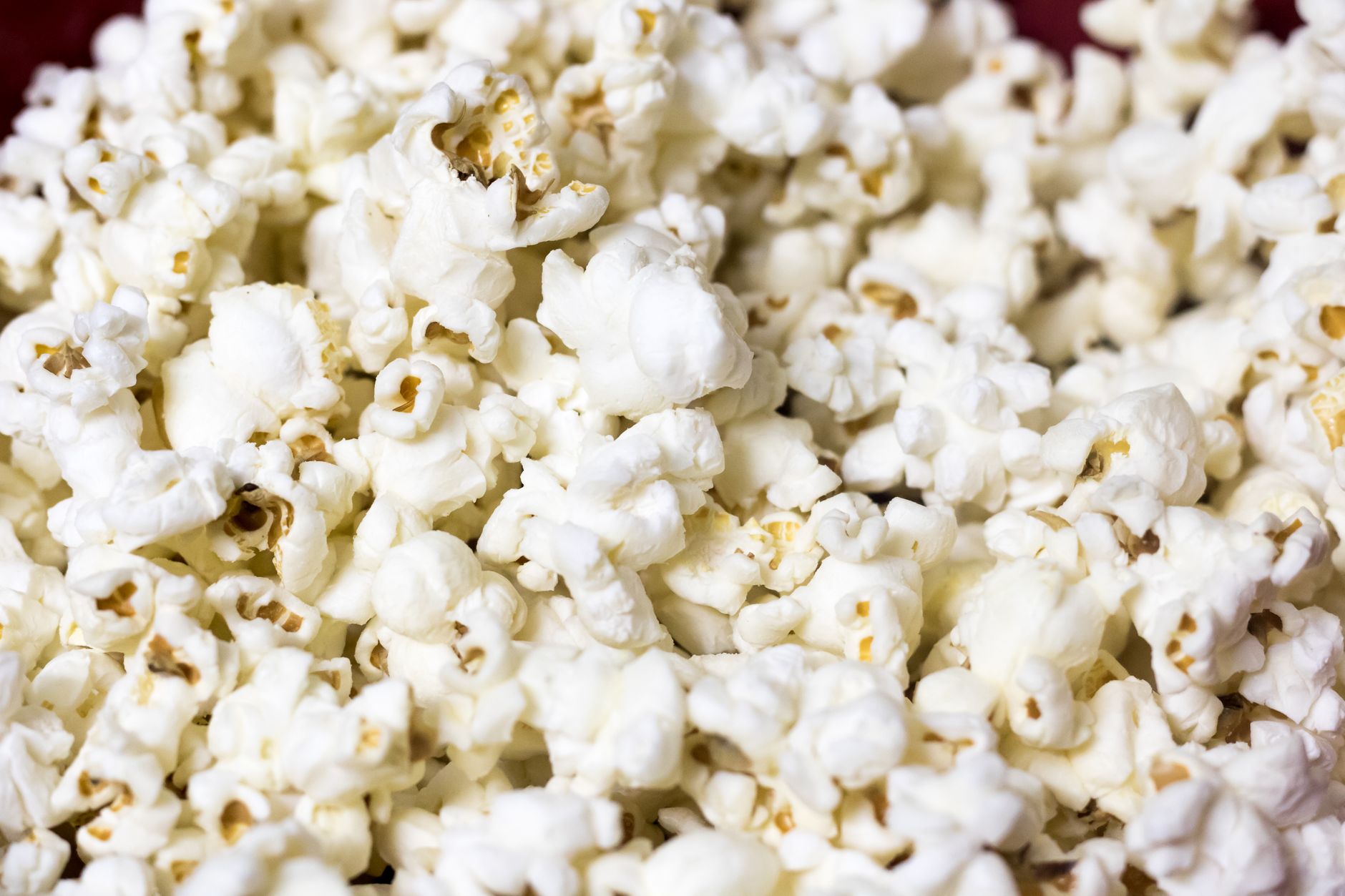 Hand holding a bowl of freshly popped popcorn with simple seasoning