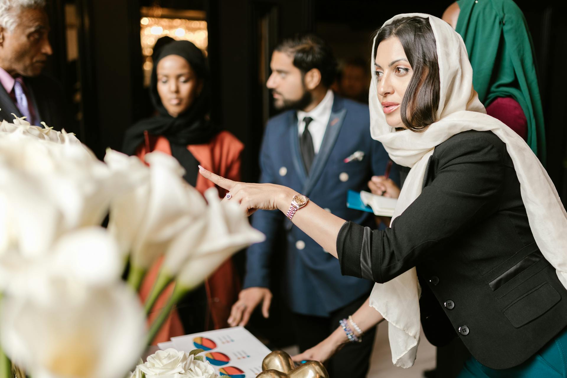 Business professionals having a discussion with charts and flowers visible on the table.