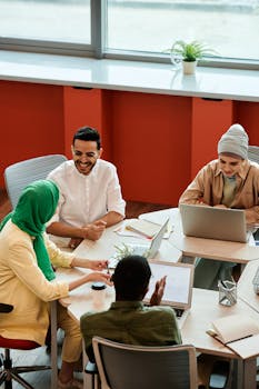 A diverse team having a meeting in a bright office space, discussing ideas and using laptops.