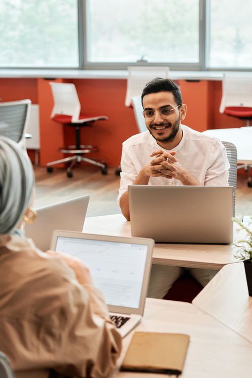 Free Two colleagues engaged in a friendly meeting in a contemporary office setting. Stock Photo