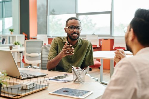 Free Two professionals engage in a casual meeting in a modern office setting. Stock Photo