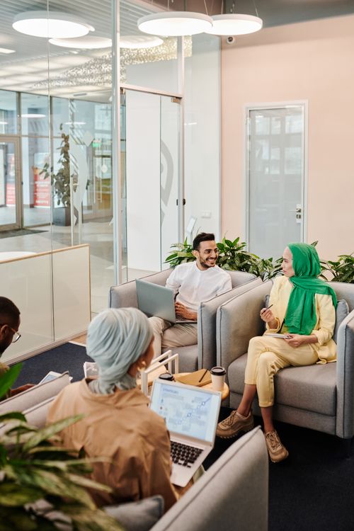 Free A diverse group of colleagues having a friendly conversation in a modern office lobby setting. Stock Photo