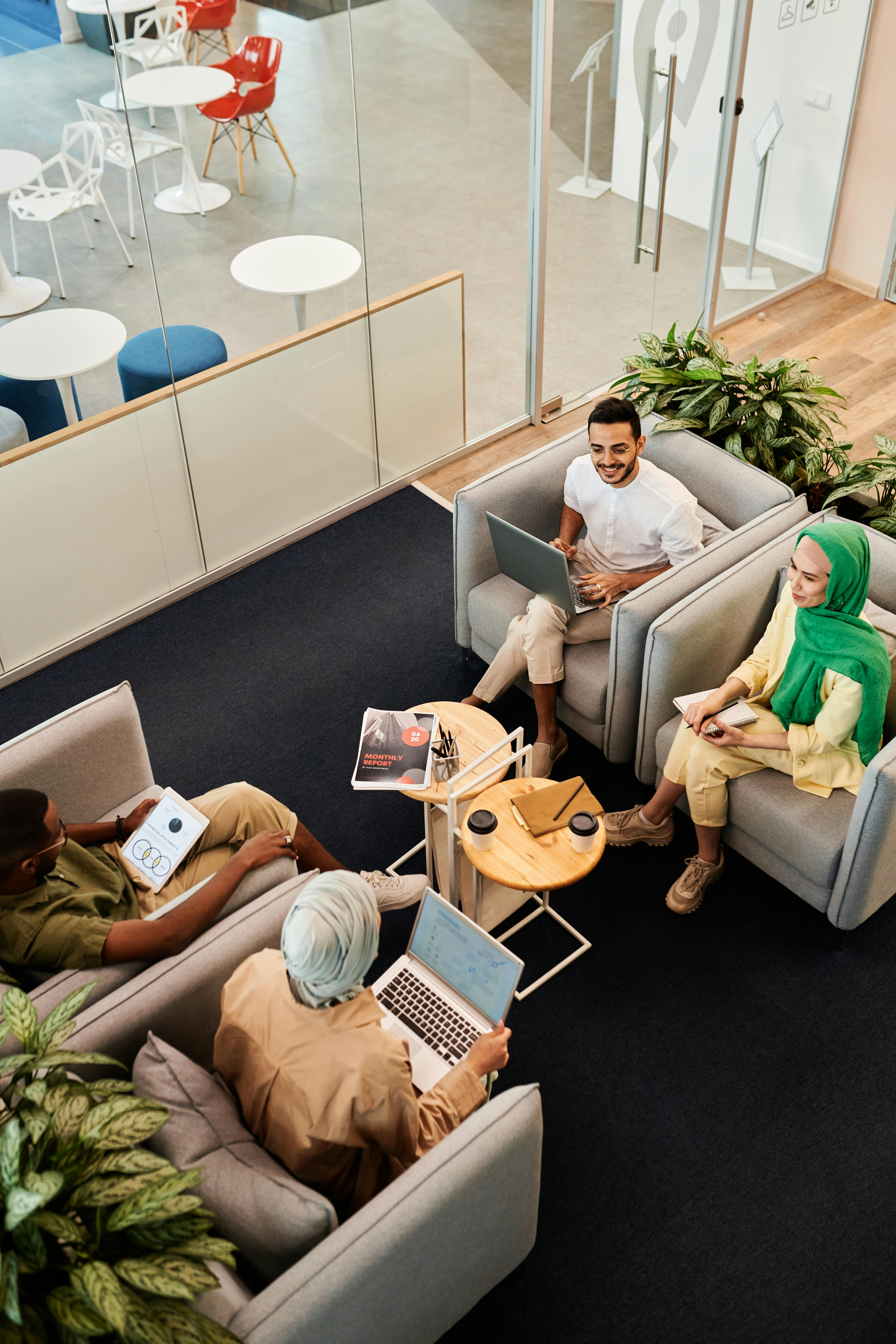 Top view of a diverse team having a friendly meeting in a modern office lobby, surrounded by plants.