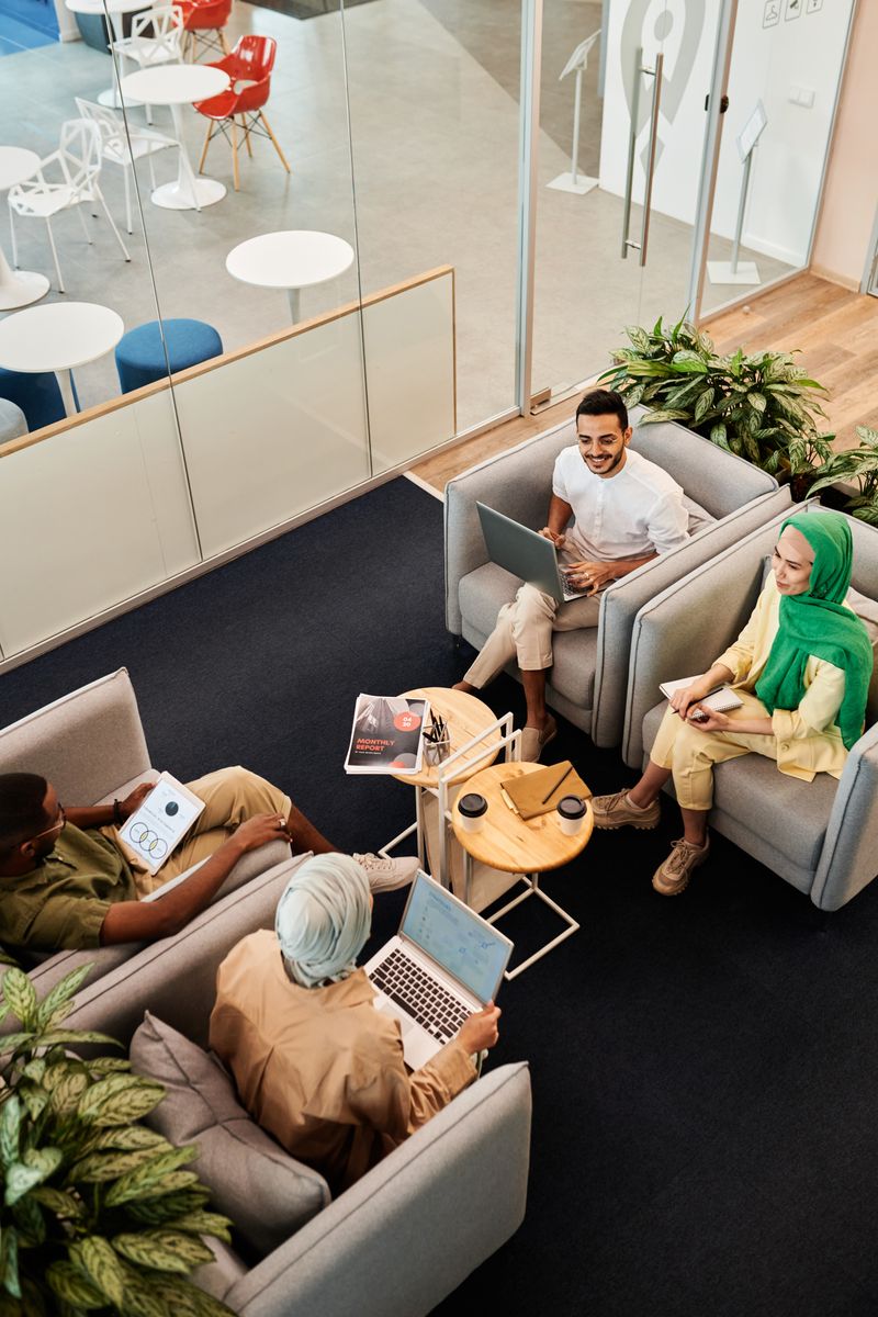 Top view of a diverse team having a friendly meeting in a modern office lobby, surrounded by plants.
