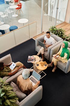 Top view of a diverse team having a friendly meeting in a modern office lobby, surrounded by plants.