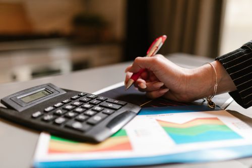 Free A business professional uses a calculator and documents during a workspace task. Stock Photo