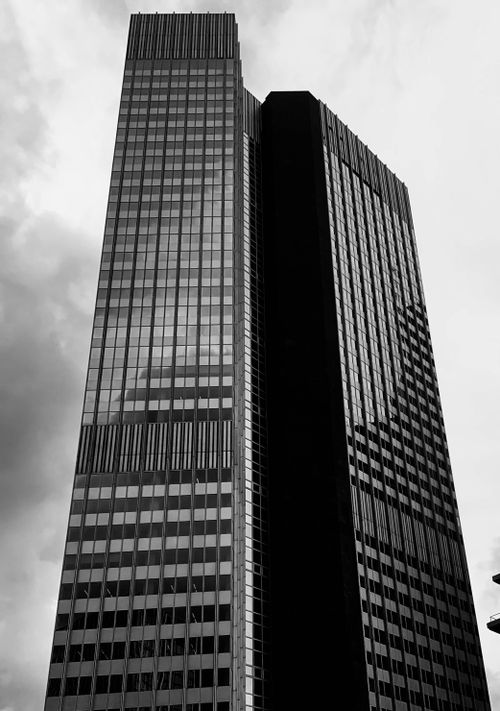 Free A striking grayscale photo of a skyscraper with glass windows against a cloudy sky. Stock Photo