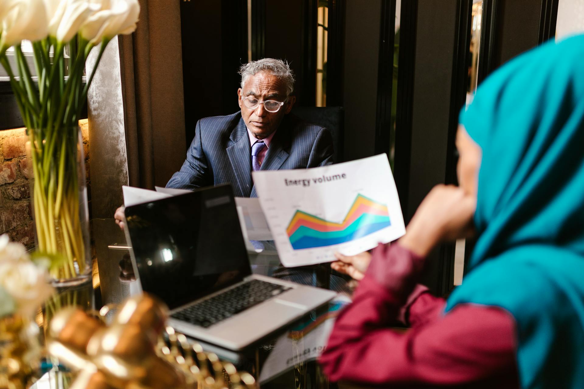 Two professionals discussing data charts during a business meeting in an office setting.