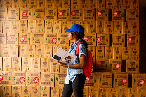 A Woman in Blue Cap Standing Near the Boxes