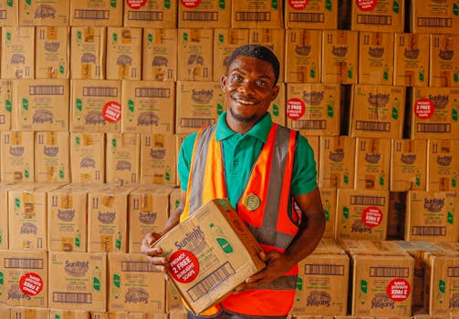 Warehouse employee holding a box while smiling in a stockroom filled with Sunlight boxes.